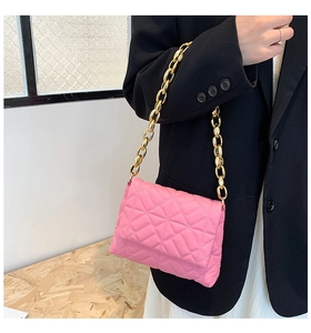 Pink quilted shoulder bag with chunky gold chain strap styled on a black blazer