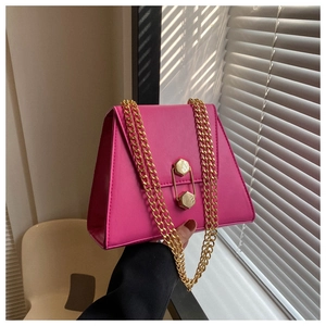 Detail of fuchsia trapezoid bag with gold chain and hexagonal metal lock in natural light