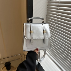 Minimalist silver faux leather backpack for women with metallic finish and gold buttons