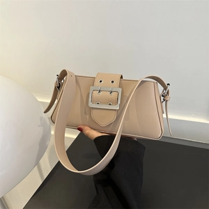 Minimalist beige underarm bag with large silver metal buckle held by model
