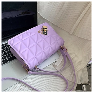 Detail of light purple quilted handbag with gold metal lock on a laptop background