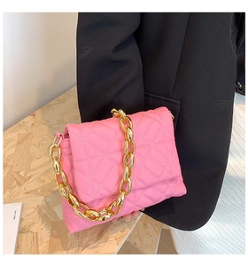 Detailed view of rose pink quilted shoulder bag with chunky gold acrylic chain decoration