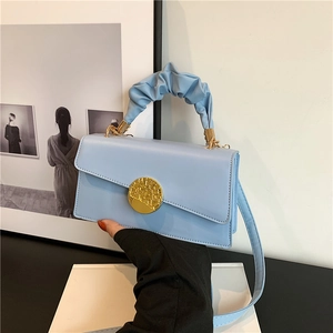 Sac bandoulière bleu clair avec boucle dorée et poignée plissée dans un cadre moderne