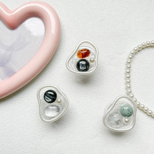 Detail view of transparent resin phone grips with orange gemstones and white pearls