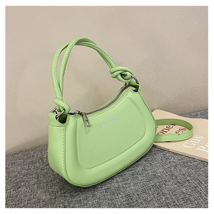 Detail of mint green crescent shoulder bag featuring knotted handle and silver zipper