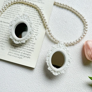 Detail of pearl phone grip strap with baroque relief mirror charms and white beads