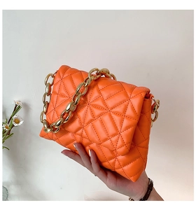 Detail shot of orange quilted PU leather handbag with chunky gold chain strap