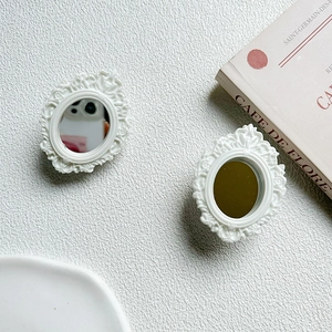 Detail of vintage white oval mirrors with floral resin frames for dollhouse or props
