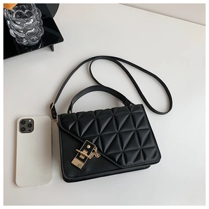 Detail of black quilted shoulder bag showing golden clasp and white phone for size reference