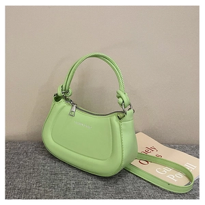 Detail of mint green dumpling bag with braided handle and fashion logo on the leather
