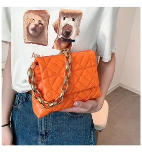 Close-up of orange quilted PU leather crossbody bag with a chunky gold chain handle
