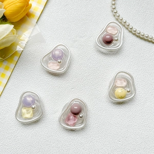 Detail of five colorful decorative phone grip charms with metallic borders on white texture
