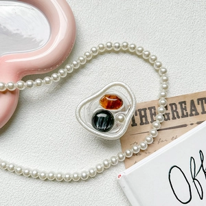 Chic expandable phone grip with amber stone and pearl on a white irregular frame