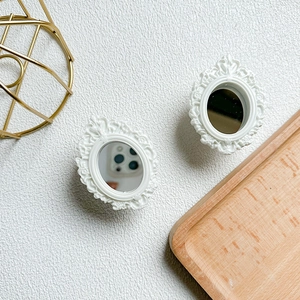 Detail of two white vintage baroque style mini makeup mirrors for phone case stands