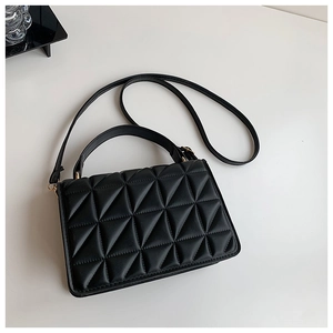 Detail view of black PU handbag featuring triangle geometric quilted texture and gold hardware