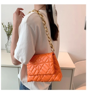 Detail of bright orange quilted PU handbag featuring a bold chunky gold chain strap