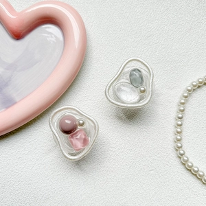 Detail of artistic resin phone grip with colorful gemstones and pearls on white texture