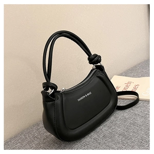 Close-up of black crescent handbag featuring white text print and silver hardware details