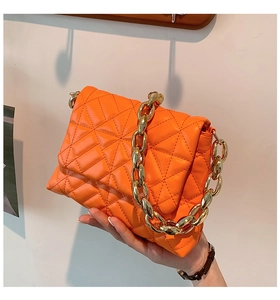 Detail of bright orange quilted PU handbag with chunky gold chain handle display