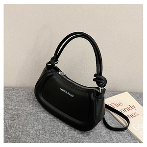 Detailed shot of a black matte shoulder bag featuring unique knotted straps and silver zipper