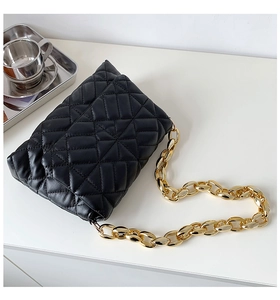Close-up of black quilted leather shoulder bag with chunky gold metal chain strap