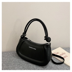 Detail of black matte leather handbag with knot accents and silver metal zipper