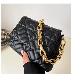 Close-up of black quilted leather shoulder bag featuring a chunky gold chain handle detail