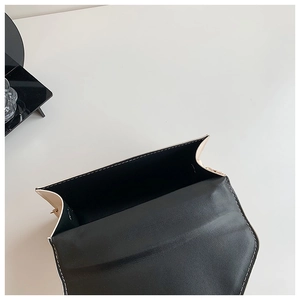 Interior view of minimalist white quilted handbag showing black lining and neat stitching