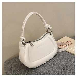 Detail of white half-moon bag featuring a knotted handle and metal zipper closure