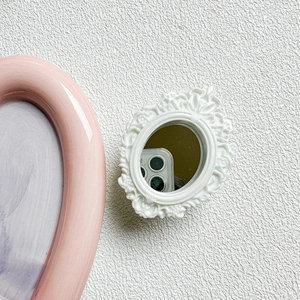 Detail of a white baroque embossed pocket mirror with vintage floral patterns for makeup