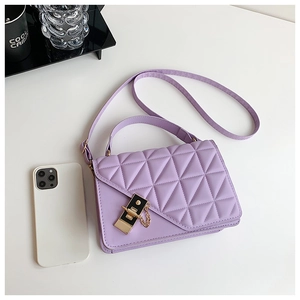 Detail of light purple quilted handbag with gold hardware lock and delicate metal chain