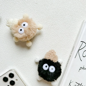 Detail of cute plush monster phone stands with knit hats in brown and black colors