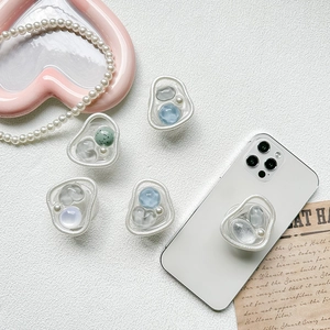 Collapsible pearl gem phone socket grip with irregular fluid frame on a smartphone