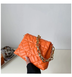 Detail of orange quilted PU leather bag with chunky gold chain strap and acrylic accents