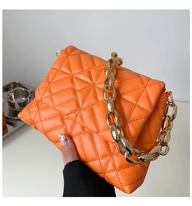 Detail of bright orange quilted PU leather shoulder bag with bold gold acrylic chain link