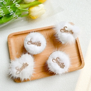 Macro shot of white plush hair accessories with Smile gold lettering and rhinestones