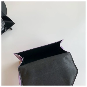 Detail view of the open purple quilted crossbody bag with black lining and gold hardware
