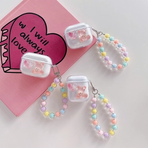Macro detail of clear AirPods case with pink glitter heart, 3D bear, and beaded strap