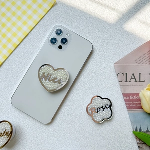 Détail du support de téléphone en forme de cœur avec texture perle et lettrage