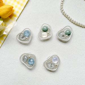 Detail of five assorted DIY resin charms with pearls and colorful beads in matte silver frames