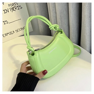 Close-up of light green half-moon bag with knotted handle and slogan print detail