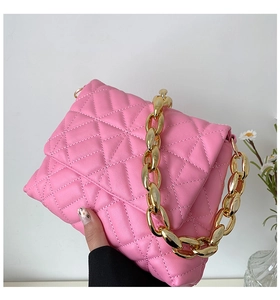 Detail of pink quilted PU leather bag with acrylic chain strap and golden hardware