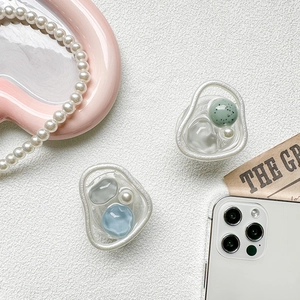 Macro view of transparent resin phone griptok with blue and green gemstone inlay