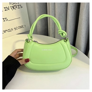 Detail of green PU leather handbag featuring knot handle design and zip closure