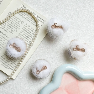 Detail of white plush heart and round phone sockets with rhinestone Smile lettering