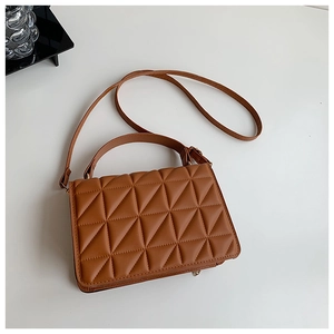 Detail of caramel brown quilted handbag with geometric triangle pattern and shoulder strap