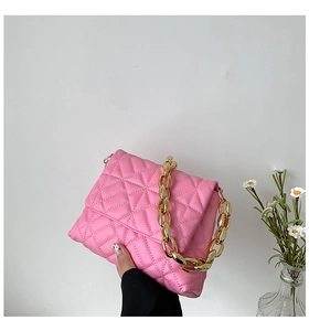 Detailed macro view of pink quilted leather shoulder bag with golden acrylic chain strap