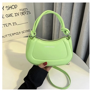 Detailed shot of green crescent bag featuring white Fashion & Bags text and knotted handle