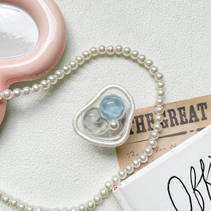 Detailed close-up of a blue bead and pearl gemstone retractable phone grip on white leather
