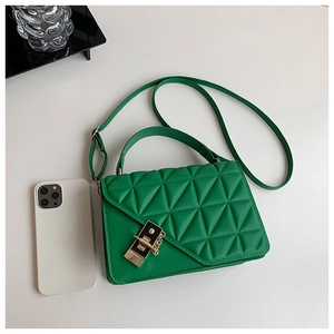 Detail of green quilted handbag showing diamond pattern texture and golden metal buckle